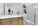 This bathroom features a framed mirror, a light wood vanity, decor, and a tiled walk-in shower at 5688 Flame Vine Way, St Cloud, FL 34771