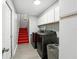 Practical laundry room with dark washer and dryer set, upper cabinets, and staircase access at 6839 Hidden Glade Pl, Sanford, FL 32771