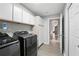 Clean laundry room with modern black washer and dryer, white cabinets, and light gray walls at 6839 Hidden Glade Pl, Sanford, FL 32771