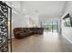 Spacious living room featuring an oversized leather couch, wood flooring and sliding glass doors to the backyard at 6839 Hidden Glade Pl, Sanford, FL 32771