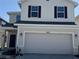 Two-story home exterior featuring a two-car garage, light-colored siding, dark shutters, and manicured landscaping at 4113 Sagefield Dr, Harmony, FL 34773