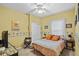 Cheerful bedroom with sunny yellow walls, comfortable bed, and a ceiling fan for added comfort at 4738 St Andrews Arc, Leesburg, FL 34748