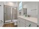 Bright bathroom featuring a glass shower, a white vanity with quartz counters, and wood look flooring at 8061 Lost Shaker Ln, Kissimmee, FL 34747