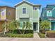 Charming two-story home featuring light green color, decorative shingles, a small balcony, and lush tropical landscaping at 8061 Lost Shaker Ln, Kissimmee, FL 34747