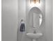 A stylish powder room featuring a pedestal sink, an oval mirror, and modern lighting at 12524 Aldershot Ln, Windermere, FL 34786
