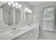 Bright bathroom featuring double sinks with round mirrors, quartz countertop, and a marble tiled shower at 2262 Stonehedge Loop, Kissimmee, FL 34743