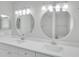 Bright bathroom with dual sinks, white cabinetry, quartz countertop, and round mirrors at 2262 Stonehedge Loop, Kissimmee, FL 34743