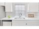 Close-up view of kitchen sink with stainless steel appliances, white countertops, and cabinetry at 2262 Stonehedge Loop, Kissimmee, FL 34743