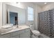 Well-lit bathroom with a white vanity, commode and shower/tub featuring a gray and white patterned shower curtain at 2613 Calistoga Ave, Kissimmee, FL 34741