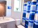 Well-lit bathroom featuring a clean design, a sink, and a blue and white shower curtain at 7858 Spectrum Dr, Reunion, FL 34747