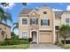 Inviting two-story home with stone accents, manicured lawn, and a paver driveway leading to an attached garage at 1011 Wood Cv, Kissimmee, FL 34743