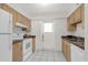 Efficient kitchen with white appliances, warm-toned cabinets, and tile flooring at 200 St Andrews Blvd # 802, Winter Park, FL 32792