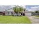 Charming single-Gathering home featuring a lush green lawn, palm trees, and a two-car garage at 643 Oregon Woods Ct, Orlando, FL 32824