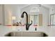 Close-up of a kitchen sink with a modern faucet, quartz countertop, and a view to the living room at 643 Oregon Woods Ct, Orlando, FL 32824