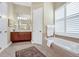 Bright bathroom featuring a soaking tub with tile surround, neutral colors, and a wood vanity at 785 Hawks Bluff, Clermont, FL 34711