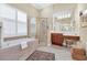 Elegant bathroom with soaking tub, glass shower, wood vanity with makeup area, and tiled floors at 785 Hawks Bluff, Clermont, FL 34711