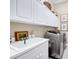 Well-equipped laundry room with white cabinetry, stainless steel washer/dryer, and decorative baskets for storage at 785 Hawks Bluff, Clermont, FL 34711