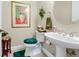 Elegant powder room features pedestal sink, toilet with teal accents, and decorative artwork and accessories at 785 Hawks Bluff, Clermont, FL 34711