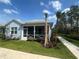 Light blue single-Gathering home with a screened-in porch, palm trees, and green lawn at 311 Pop Top Ln, Daytona Beach, FL 32124