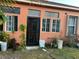 View of the back of the house, showing windows and a secure metal door and overgrown landscaping at 675 Elbridge Dr, Kissimmee, FL 34758