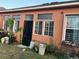 View of the back of the house, showing windows and a secure metal door and overgrown landscaping at 675 Elbridge Dr, Kissimmee, FL 34758