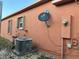 Exterior view of home with an air conditioner and dish satellite on textured terracotta colored wall at 675 Elbridge Dr, Kissimmee, FL 34758