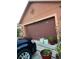View of two car garage with dark brown door and plants in the driveway at 675 Elbridge Dr, Kissimmee, FL 34758