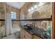 Elegant bathroom features a black granite countertop, vessel sink, and travertine tile in the shower and backsplash at 2198 W Highway 329, Citra, FL 32113