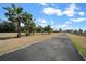 Scenic view of a long driveway leading up to a charming home with a metal roof, surrounded by palm trees at 2198 W Highway 329, Citra, FL 32113