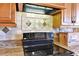 Close-up of a kitchen showcasing wooden cabinets, a sleek black range, and a decorative tile backsplash at 2198 W Highway 329, Citra, FL 32113