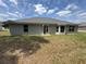 Back exterior view of home with green grass and an open patio space at 7051 Sw 64Th Ter, Ocala, FL 34476