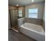 Modern bathroom with a glass-enclosed shower, large tub and tiled surround at 7051 Sw 64Th Ter, Ocala, FL 34476