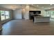 Open layout featuring gray floors and vaulted ceiling with modern kitchen in the background at 7051 Sw 64Th Ter, Ocala, FL 34476