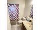 Bathroom features a vanity, toilet, tile floor, and shower with colorful curtain at 10300 Sw 98Th Ter, Ocala, FL 34481