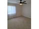 Bright bedroom featuring a ceiling fan, plush carpeting, and a large window with sheer curtains at 9951 Sw 62Nd Ter, Ocala, FL 34476