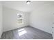 Sunlit bedroom with a large window and modern gray wood-look floors at 13026 Ne 6 Pl, Silver Springs, FL 34488
