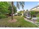 Backyard with green grass, mature trees, and covered patio attached to a yellow two-story home at 1226 Se 9Th Ave, Ocala, FL 34471