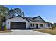 White farmhouse exterior with black garage door and landscaping at Tbd W C 466 # Lot 1, Oxford, FL 34484