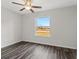 Simple bedroom with large window, ceiling fan, and dark laminate floors at 16588 Sw 25Th Terrace Rd, Ocala, FL 34473