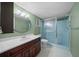 Bathroom featuring a wood vanity, round mirror, and tiled glass-enclosed shower at 8655 Sw 98Th Street Rd # G, Ocala, FL 34481
