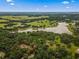 Expansive aerial view of home nestled in a lush, green landscape with nearby lake and golf course in the distance at 15235 Se 63Rd Ave, Summerfield, FL 34491