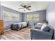 Bedroom featuring wood-look floors, neutral blue walls, ceiling fan, and natural light from multiple windows at 15235 Se 63Rd Ave, Summerfield, FL 34491