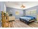 Bedroom with wood-look floors, blue walls, and a ceiling fan. Double windows let in plenty of light at 15235 Se 63Rd Ave, Summerfield, FL 34491