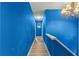 Bright hallway featuring blue walls, wood-look floors, and a classic chandelier, creating a welcoming path at 15235 Se 63Rd Ave, Summerfield, FL 34491