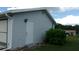 Gray storage shed with white door and landscaping at 10926 Sw 78Th Ct, Ocala, FL 34476