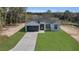 Aerial view of a charming single-story home with a lush green lawn and concrete driveway, surrounded by trees at 35 Locust Terrace Way, Ocala, FL 34472