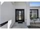 Close-up of a modern black front door with sidelights, set in a white exterior with manicured landscaping at 35 Locust Terrace Way, Ocala, FL 34472