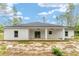 Rear exterior view of a white home with a covered patio, ceiling fans, and dark roof at 4444 Sw 118 Ter, Ocala, FL 34481
