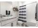 Well-lit bathroom featuring a modern vanity, decorative shelves, and a shower with a striped curtain at 8996 Sw 49Th Cir, Ocala, FL 34476