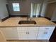 Kitchen island with white cabinets, stainless steel sink, and granite countertops offer modern appeal at 15747 Sw 47Th Avenue Rd, Ocala, FL 34473